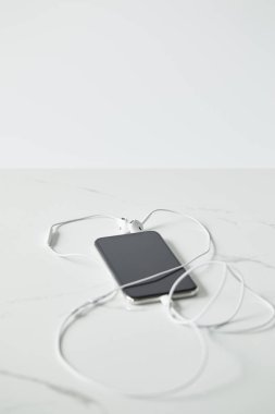 boş ekran ve gri renkte yalıtılmış kulaklıklar ile akıllı telefonun seçici odağı