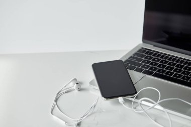 gri renkte yalıtılmış bağlı kulaklıkları olan dizüstü bilgisayar ve akıllı telefon