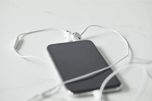 Selective Focus Earphones Connected Smartphone Blank Screen White Surface — Stock Photo, Image