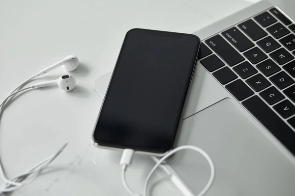 검은색 키보드가 표면에 화면이 스마트폰과 이어폰 — 스톡 사진