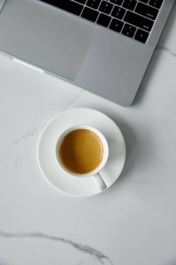 beyaz mermer yüzeyde siyah tuş takımı ile latte ve laptop ile kahve bardağı üst görünümü