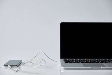 gri üzerinde izole bağlı kulaklıklar ile boş ekran ve akıllı telefon ile Laptop