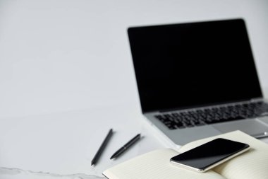 Not defteri, akıllı telefon ve dizüstü bilgisayar seçici odak gri üzerinde boş ekran izole
