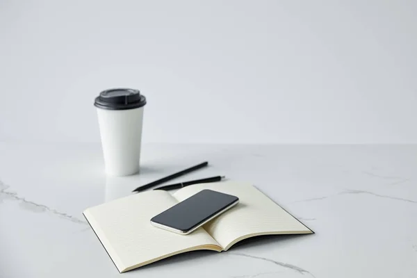 空白の画面 ノートブックと灰色に分離された使い捨てカップとスマートフォン — ストック写真