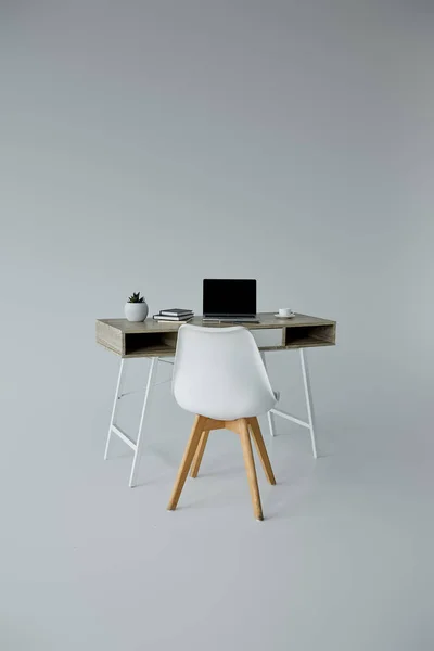 Witte Stoel Tafel Met Laptop Boeken Bloempot Grijze Achtergrond — Stockfoto