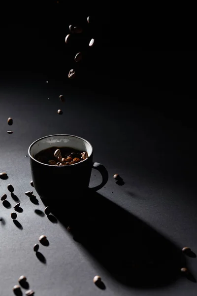 暗い質感の表面上のコーヒーカップとコーヒーの穀物 — ストック写真