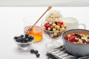 çilek ile müsli, fındık ve bal kase beyaz tablo üzerinde Besleyici kahvaltı için servis gri üzerinde izole