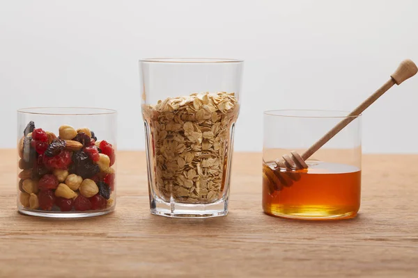 灰色に分離された木製のテーブルの乾燥した果実 ナッツ オーツ麦フレークと蜂蜜とメガネ — ストック写真