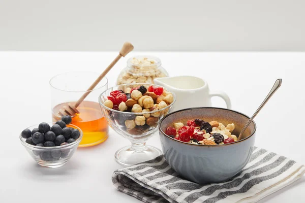 灰色に孤立した白いテーブルの上の朝食のためのベリー ナッツと蜂蜜とミューズリー — ストック写真