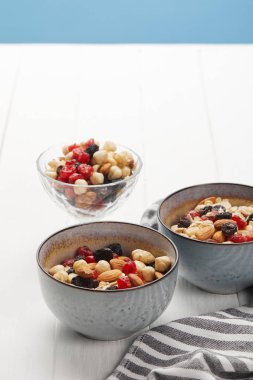 bowls with muesli, dried berries and nuts served for breakfast isolated on blue clipart
