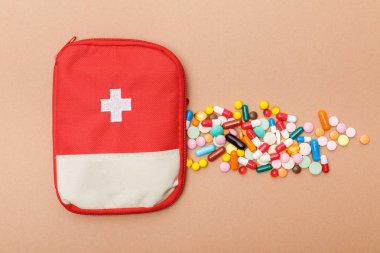 Top view of first aid kit bag and colorful pills on brown surface clipart