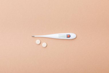 Kahverengi yüzeyde termometre ve hapları üst görünümü