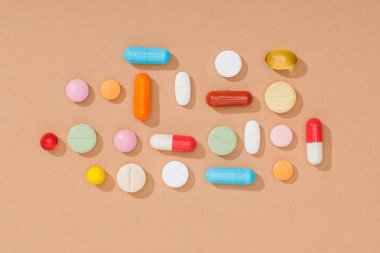 Top view of colorful pills on brown surface clipart