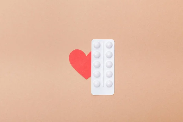 茶色に孤立した丸薬と紙の心臓の水疱のトップビュー — ストック写真