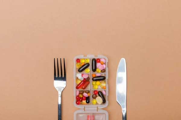 棕色表面有药丸和餐具的容器的顶视图 — 图库照片