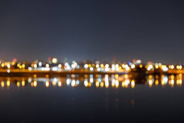 defocused aydınlatmalı binalar ve nehir ile karanlık Cityscape