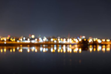 dark cityscape with defocused illuminated buildings and river clipart