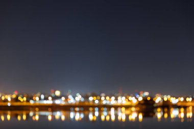 Geceleri binalar, bokeh ışıkları ve nehir ile karanlık Cityscape