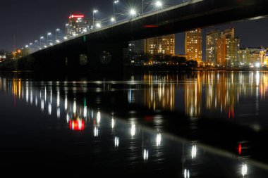 Işıklı köprü ve geceleri nehre yansıma ile karanlık Cityscape