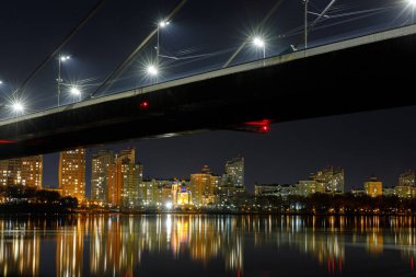 karanlık Cityscape Köprüsü, geceleri nehir ve aydınlatılmış evlerde yansıma
