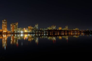 Işıklı binalar, nehir ve gece gökyüzü ile pitoresk karanlık Cityscape