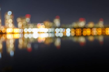 Işıklı binalar, yansıma ve bokeh ışıkları ile bulanık karanlık Cityscape
