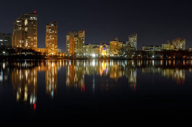 Geceleri suya yansıma ile ışıklı binalar ile karanlık Cityscape