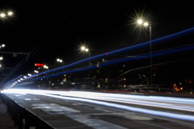 long exposure of lights on road at nighttime near illuminated buildings clipart