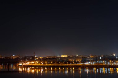 aydınlatılmış binalar ve geceleri nehirde yansıma ile sakin bir şehir manzarası