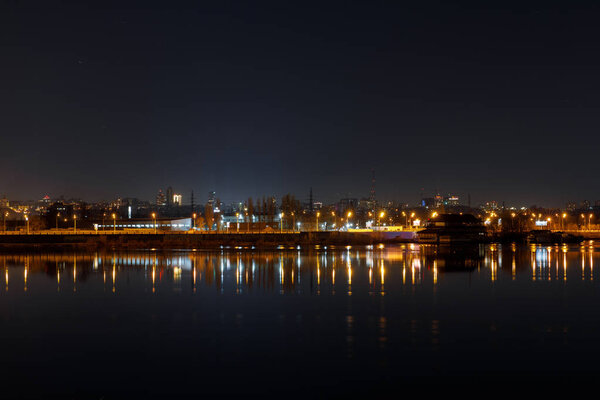 dark cityscape with illuminated buildings and calm river at nigth