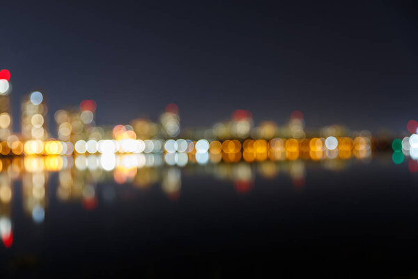 blurred dark cityscape with illuminated buildings and reflection