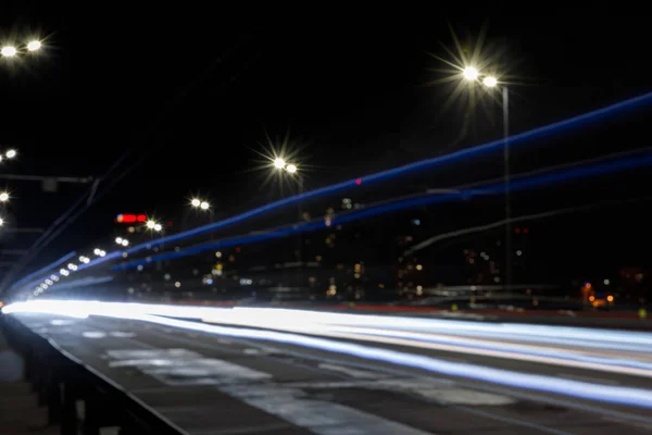 夜间在照明建筑物附近长时间暴露道路上的灯光 — 图库照片