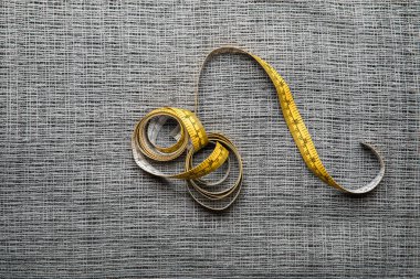 top view of yellow measuring tape on textured sackcloth background clipart