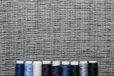 top view of blue and grey thread coils in row on sackcloth with copy space clipart