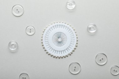şeffaf giyim düğmeleri ve yuvarlak konteyner gri üzerinde izole dikiş pimleri ile üst görünümü 