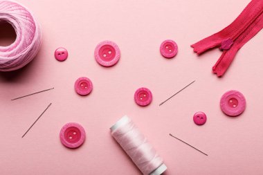Giysi düğmeleri üst görünümü, iplik bobin ve dikiş malzemeleri pembe izole