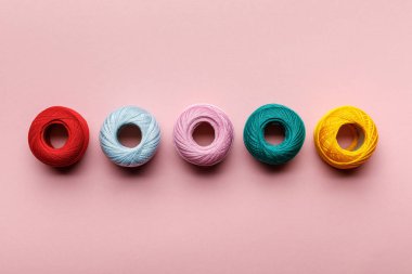 pembe üzerinde düzenlenmiş renkli pamuk örgü iplik topları üst görünümü