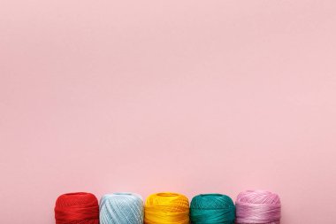 top view of arranged colorful cotton knitting yarn balls isolated on pink with copy space