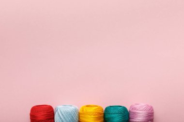 top view of arranged colorful cotton knitting yarn balls isolated on pink with copy space clipart