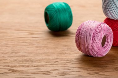 colorful cotton knitting yarn balls on wooden table with copy space clipart
