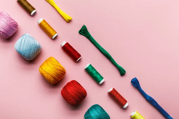 カラフルな編み糸のボール 刺繍糸とピンクのスレッドコイルのトップビュー — ストック写真