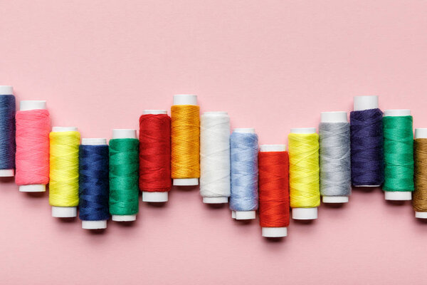 top view of arranged colorful thread coils on pink