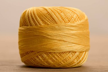 close up view of yellow cotton knitting yarn ball on beige clipart