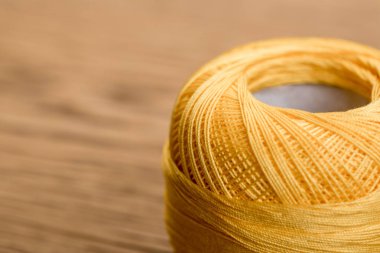 selective focus of yellow cotton knitting yarn ball on wooden table with copy space clipart