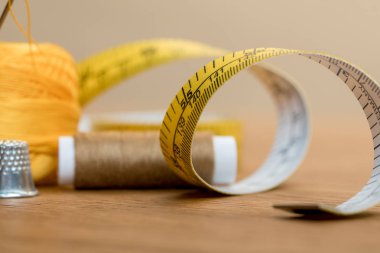 selective focus of measuring tape with thread coil on wooden table clipart