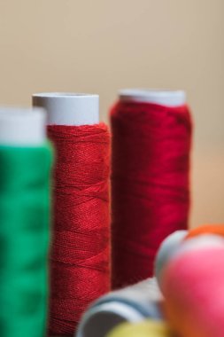 bej üzerinde izole kırmızı pamuk iplik bobinleri seçici odak