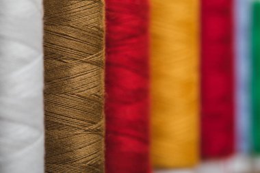 selective focus of colorful cotton thread coils in row with copy space clipart
