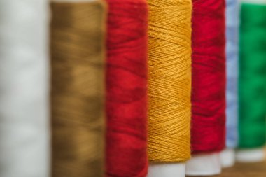 selective focus of colorful cotton thread coils in row with copy space clipart
