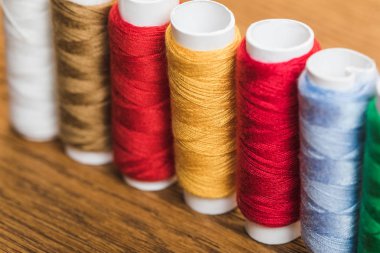 colorful cotton thread coils in row on wooden surface clipart