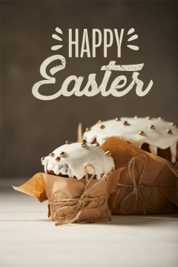kahverengi arka planda Mutlu Paskalya yazısı ile beyaz masa üzerinde Craft kağıt geleneksel dekore Paskalya kek